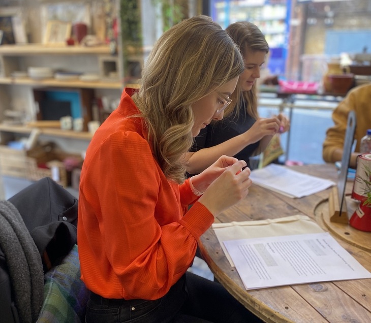 London Repair Week: A woman in a orange blouse repairing a piece of fabric