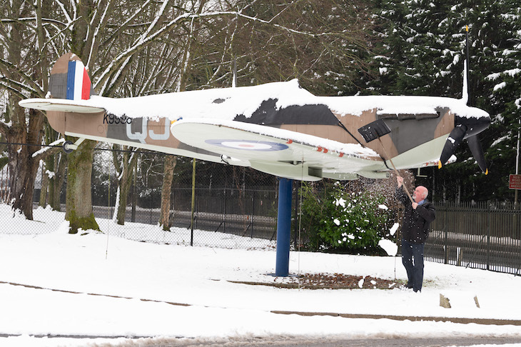 A man brushes snow off a Spitfire