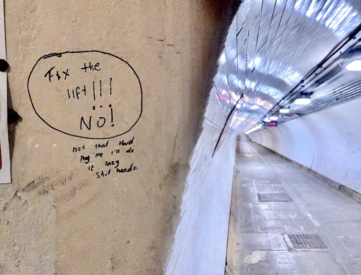 A view through the tunnel, with graffiti saying Fix the Lift