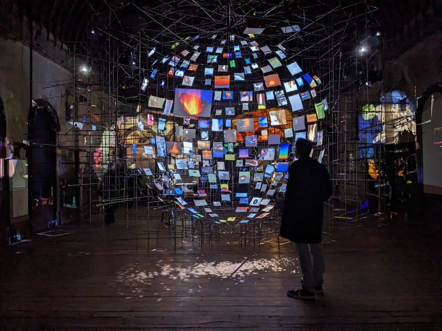 A person stands in front of the installation which looks like a globe made up of many screens