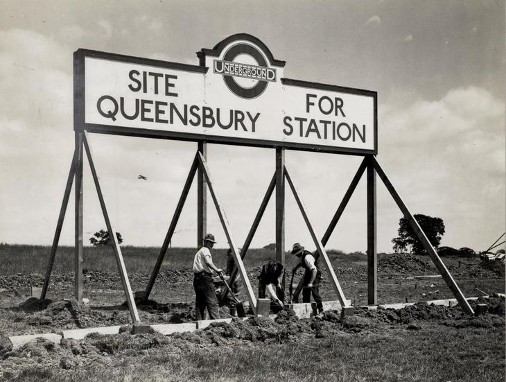 Workers beneath a huge sign for Queesnbury