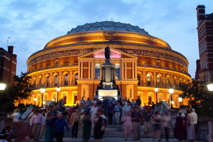 Crowds of people outside the Albert Hall, illuminated in gold