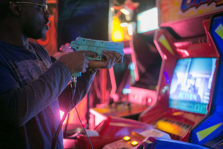 Play arcade games in London: Someone holding a plastic gun to a screen
