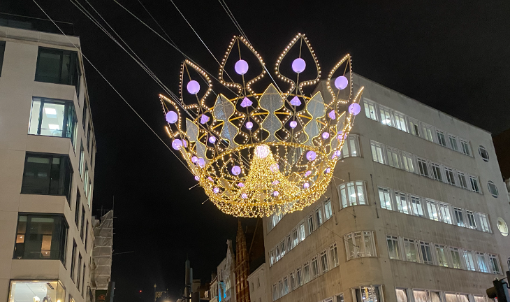 London Christmas lights 2023: a glowing golden crown suspended above Bond Street at night