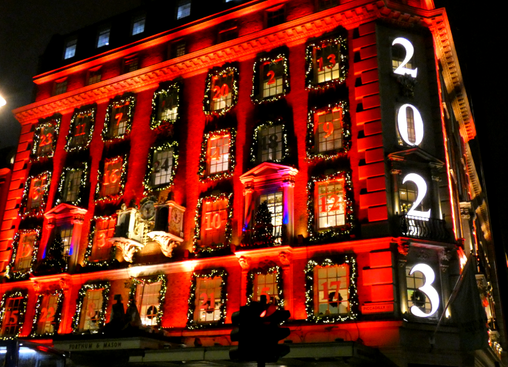 Exterior of Fortnum & Mason bathed in red light with a different number on each window, and '2023' written vertically down the corner