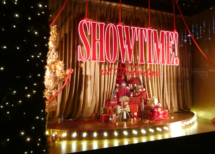 A window display with a pile of presents wrapped in red and the word 'Showtime!' written above