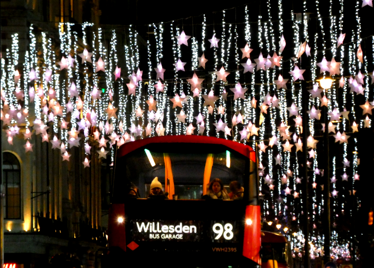 A 98 bus driving beneath curtains of glowing stars on Oxford Street