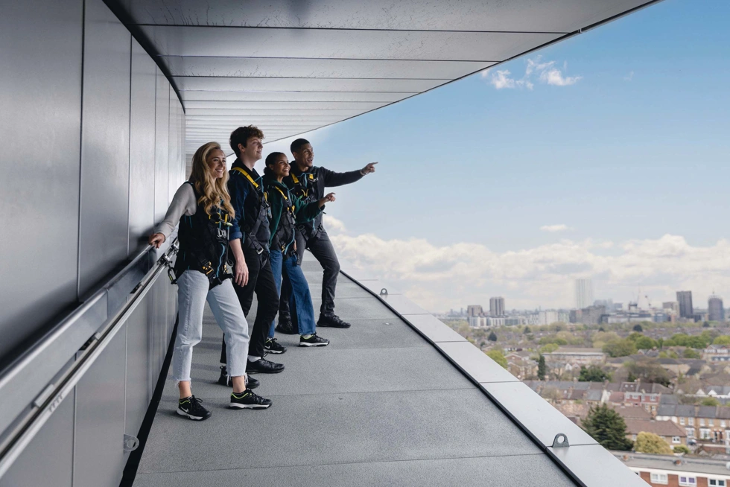 Four people standing on a ledge, looking out at the view