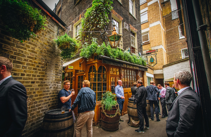 People in suits drinking outside an alleyway pub